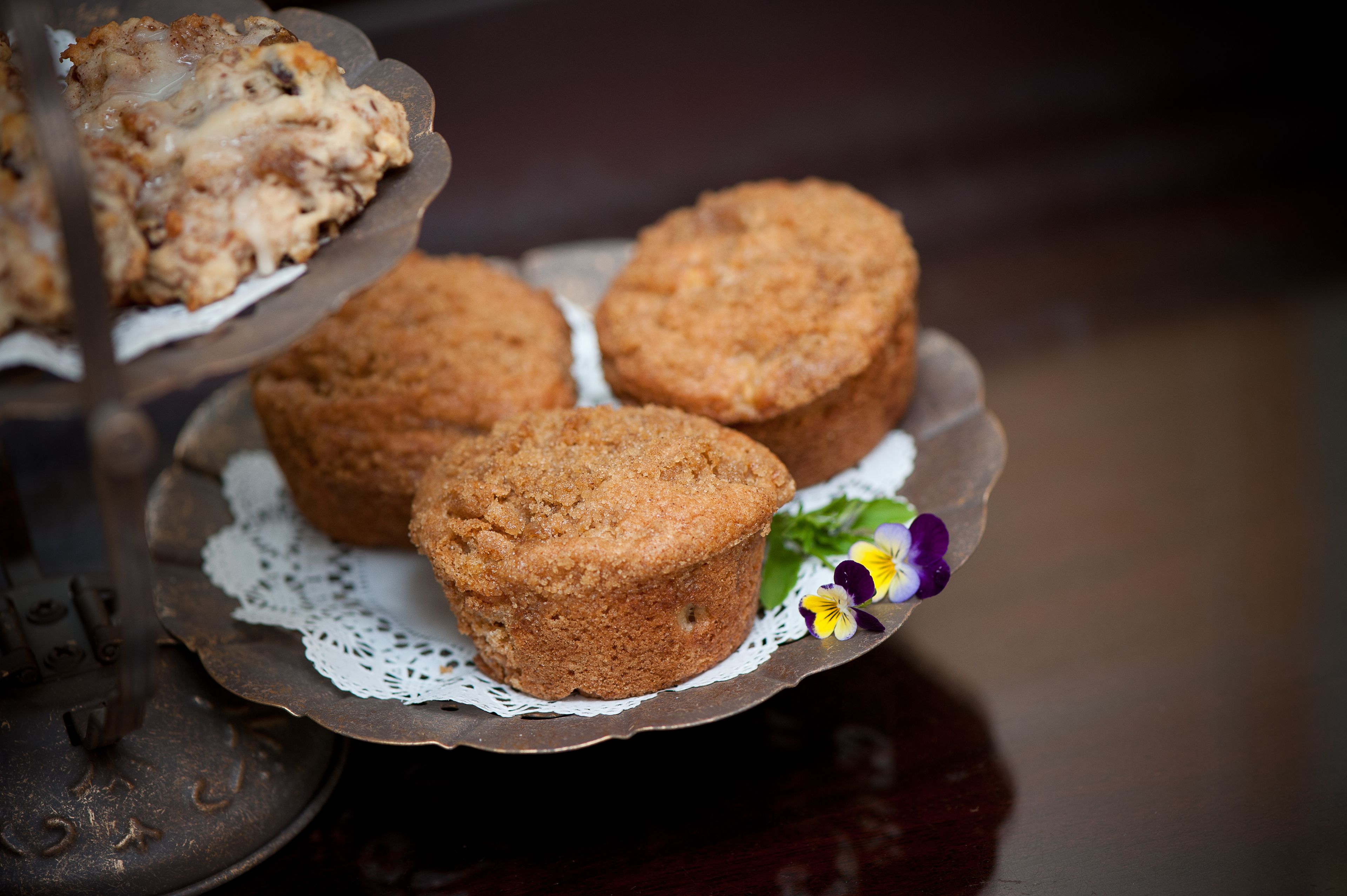 A plate with three muffins and a decorative doily.