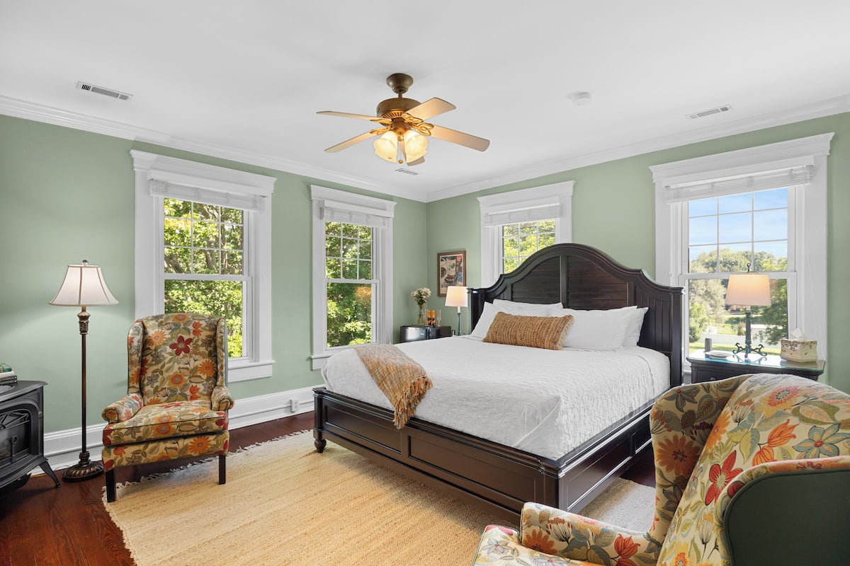 A bedroom with a bed, a chair, a nightstand, and a ceiling fan.