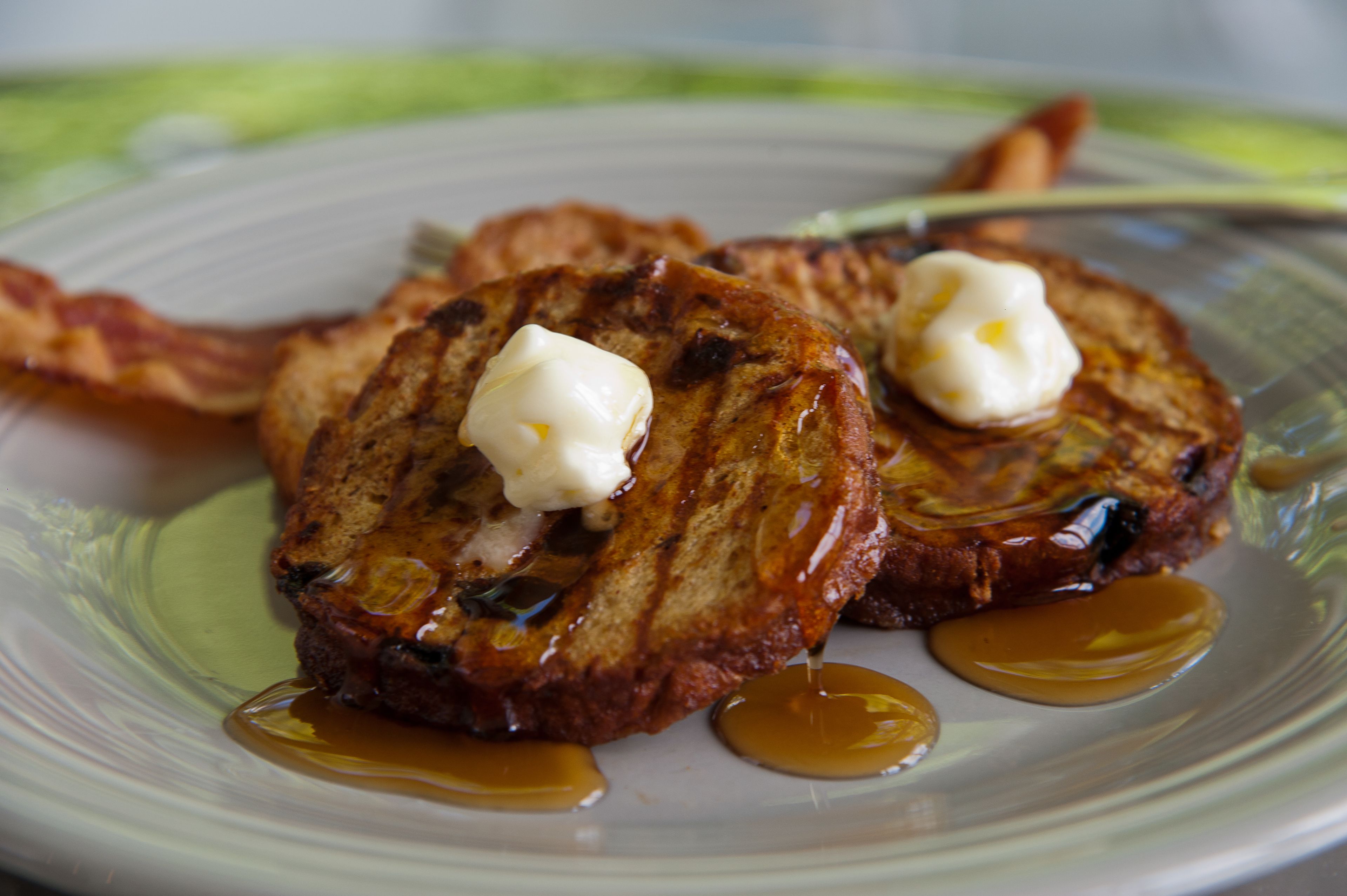 A plate of French toast with syrup and butter.