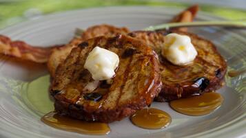 A plate of French toast with syrup and butter.
