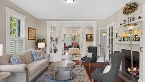 A living room with a sofa, armchair, coffee table, fireplace, and a dining area in the background. - Steeles Tavern Manor (Raphine)