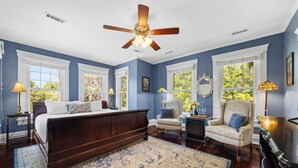 A bedroom with a large bed, a ceiling fan, and a view of the outdoors through the windows. - Steeles Tavern Manor (Raphine)