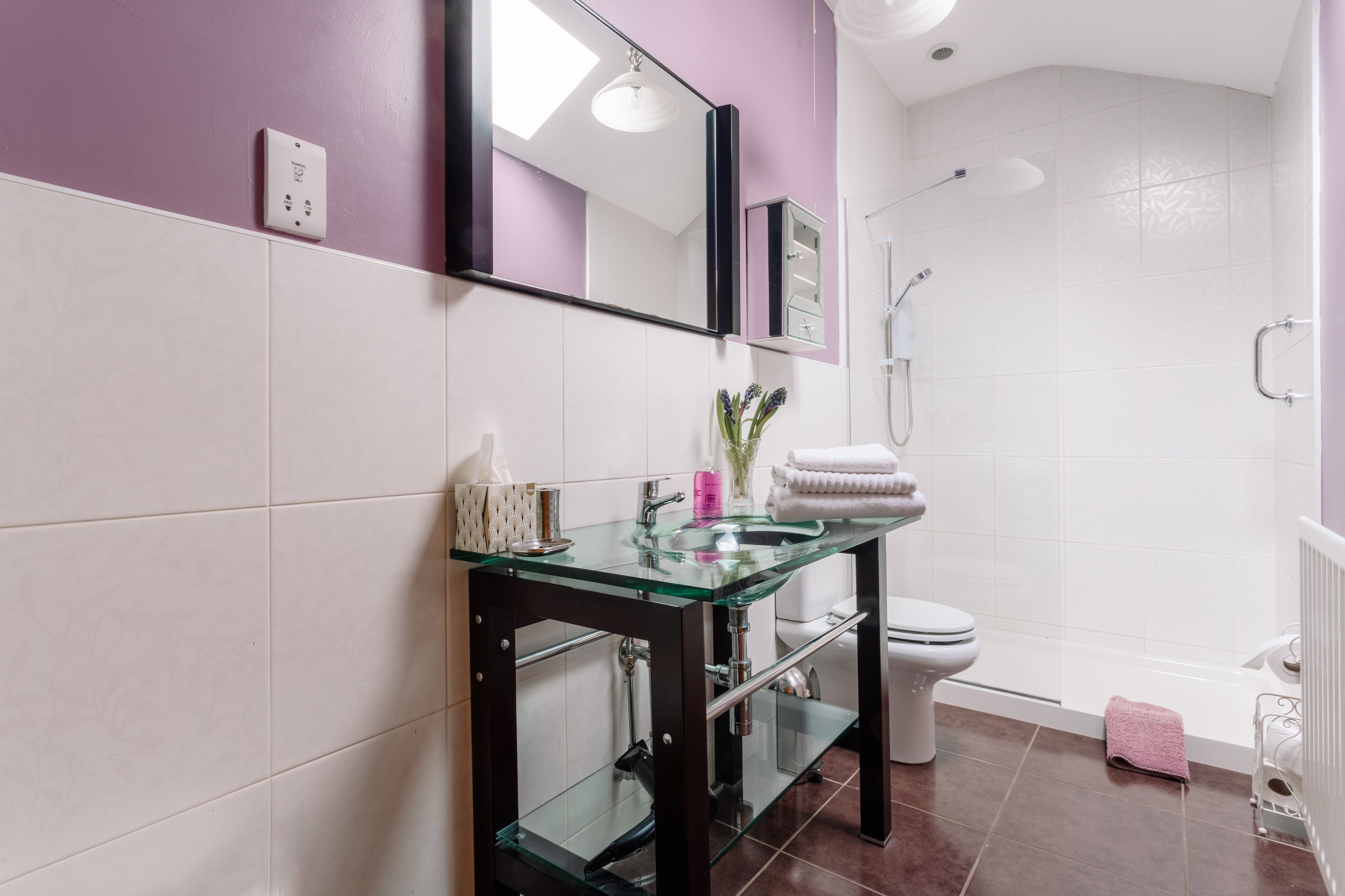 Une salle de bain moderne avec un lavabo en verre, des toilettes blanches et un espace douche.