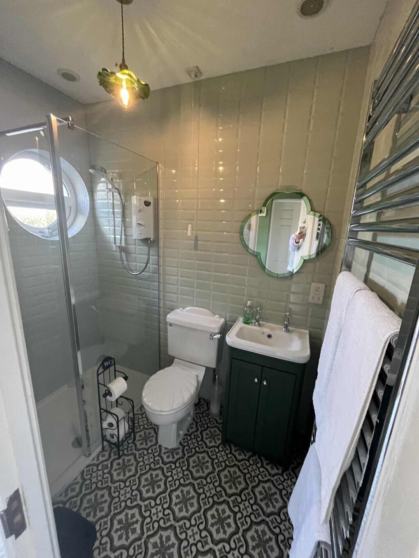 A bathroom with a shower, toilet, sink, and a mirror.