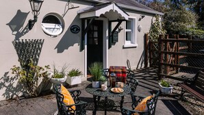 A quaint cottage with a round window, a door, and a small porch area. - Brookhall Cottages (Lisburn)