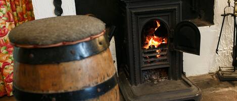 Un barril de madera, una estufa negra con fuego y una puerta con cortina.