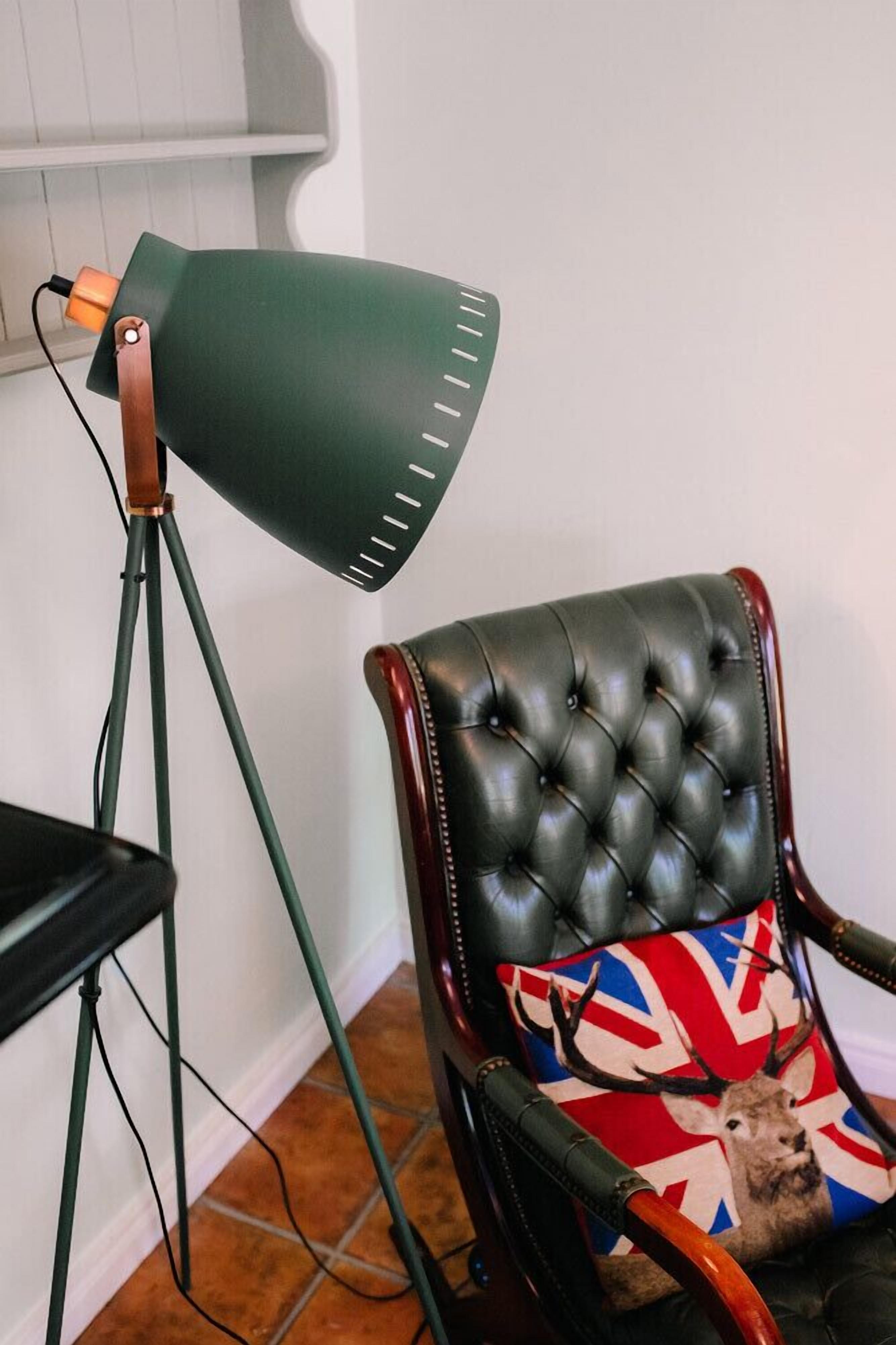 Ein Sessel mit Union-Jack-Kissen und einer grünen Stehlampe.