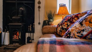 A cozy room with a fireplace, a sofa, and a lamp. - Brookhall Cottages (Lisburn)