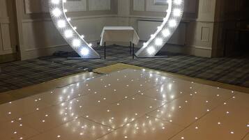 Una habitación con una instalación de luces con forma de corazón en el suelo y una mesa con mantel blanco.