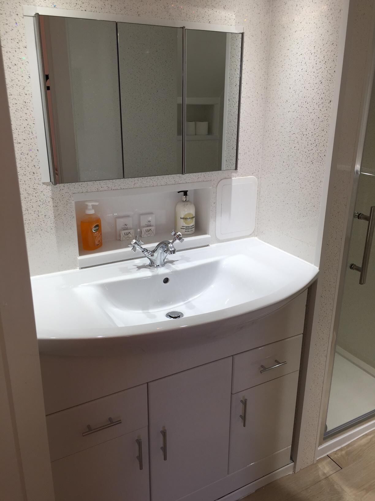 A bathroom with a white sink, a mirror, and a shower enclosure.