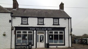 A white building with a black sign reading "The Village Inn." - The Village Inn and Kirtle House B&B (Lockerbie)