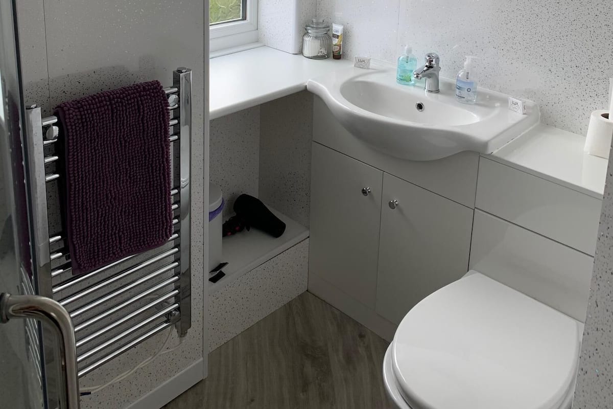 A modern bathroom with a white sink, a round mirror, and a toilet.