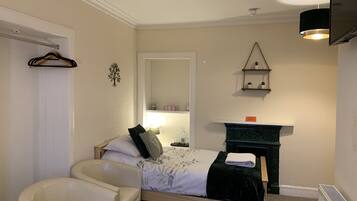 A bedroom with a bed, a chair, a dresser, a mirror, and a shelf with plants.