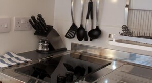 A modern kitchen with a glass-top stove, stainless steel appliances, and a knife block. - Bull Farm Studios (Winchester)