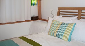 A bed with white bedding and a striped pillow, a wooden headboard, and a window with curtains. - Bull Farm Studios (Winchester)