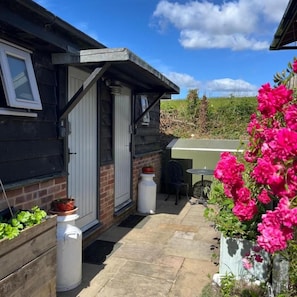 A residential property with a patio area, a door, and a garden with flowers. - Bull Farm Studios (Winchester)