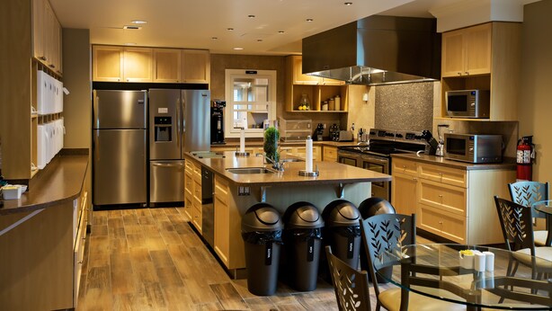 Una cocina moderna con electrodomésticos de acero inoxidable, armarios de madera y una mesa de comedor de vidrio.