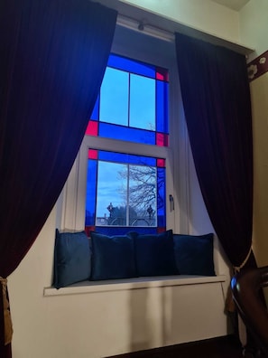 A room with a window featuring blue-tinted glass panes and dark curtains. -  Norcroft Guest House Vegetarian B&B. (Penrith)