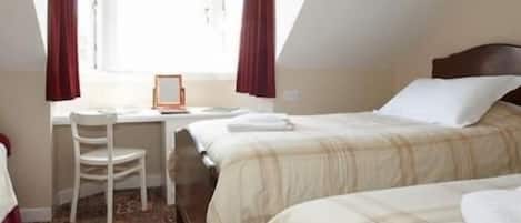 Un dormitorio con dos camas, un escritorio y una silla.