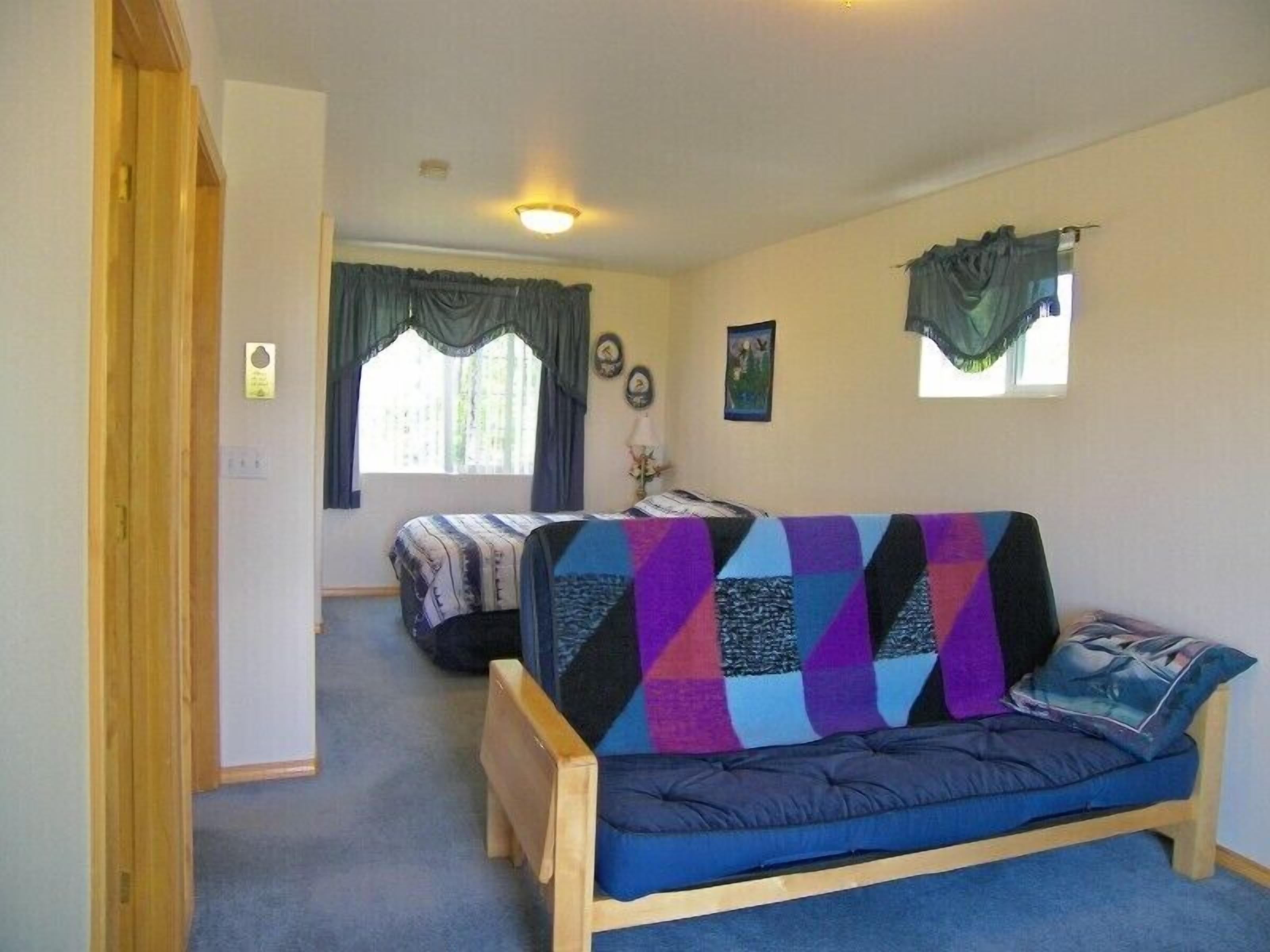 A compact room with a bed, a sofa, and a small table.