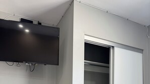 Una habitación con un televisor de pantalla plana montado en la pared, una puerta corredera para el armario y un zócalo blanco.