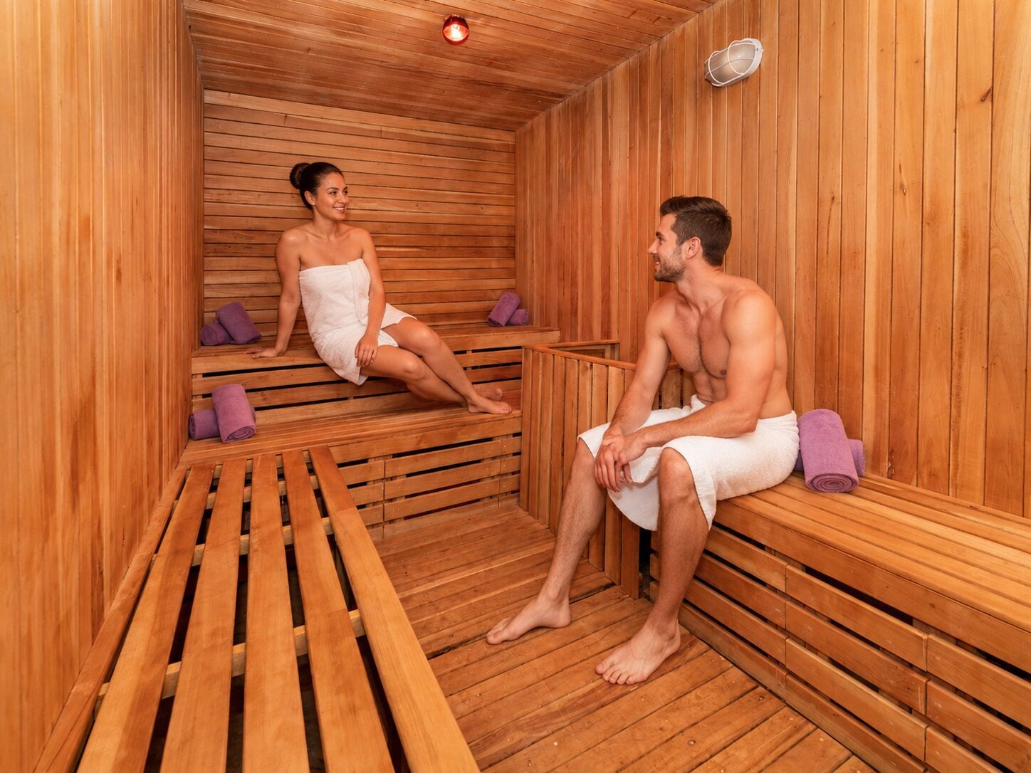 Una sauna con bancos de madera y un banco al frente.