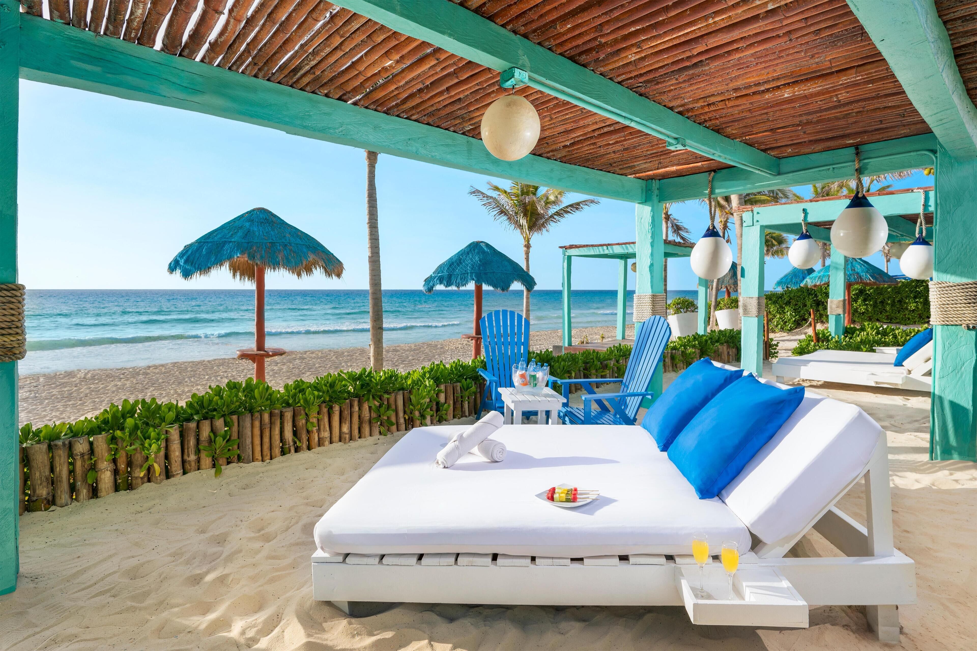 Na praia, areia branca, barracas de praia de cortesia, espreguiçadeiras 