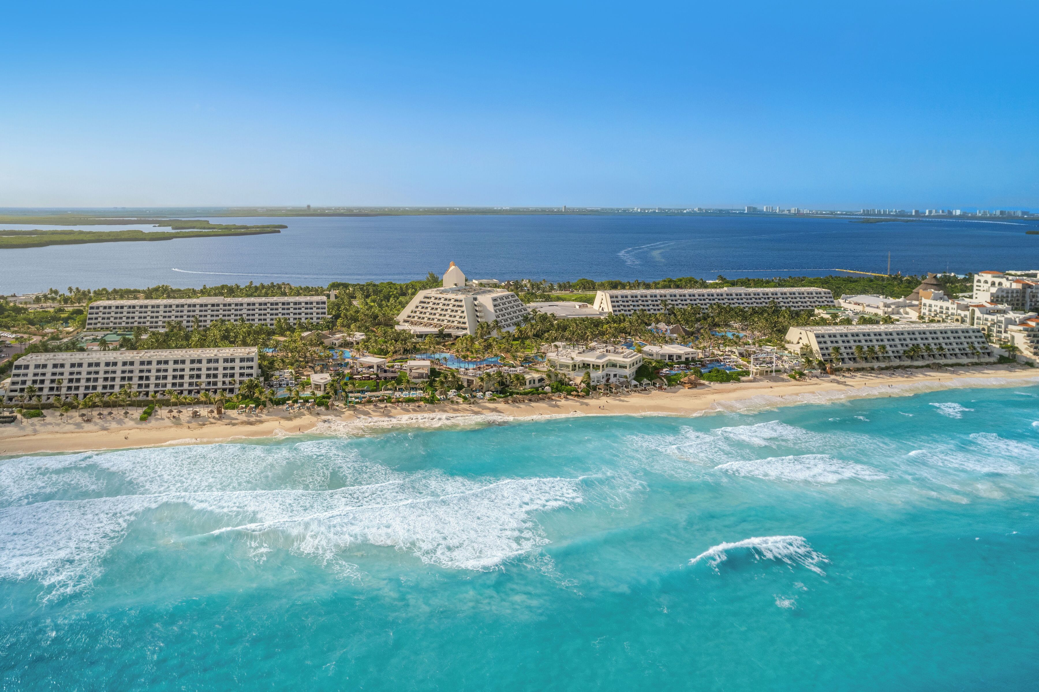 Ein Resort mit mehreren Hotelgebäuden, einem Strand und Blick auf den Ozean.