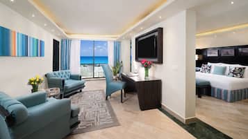 A modern living room with a sofa, armchair, and a desk with a flat-screen TV.