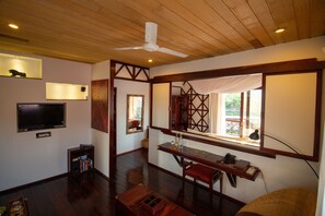 A room with a wooden ceiling, a ceiling fan, a television, a desk with a lamp, and a window with a view of the outdoors. - Viewpoint Ecolodge (Nyaungshwe)