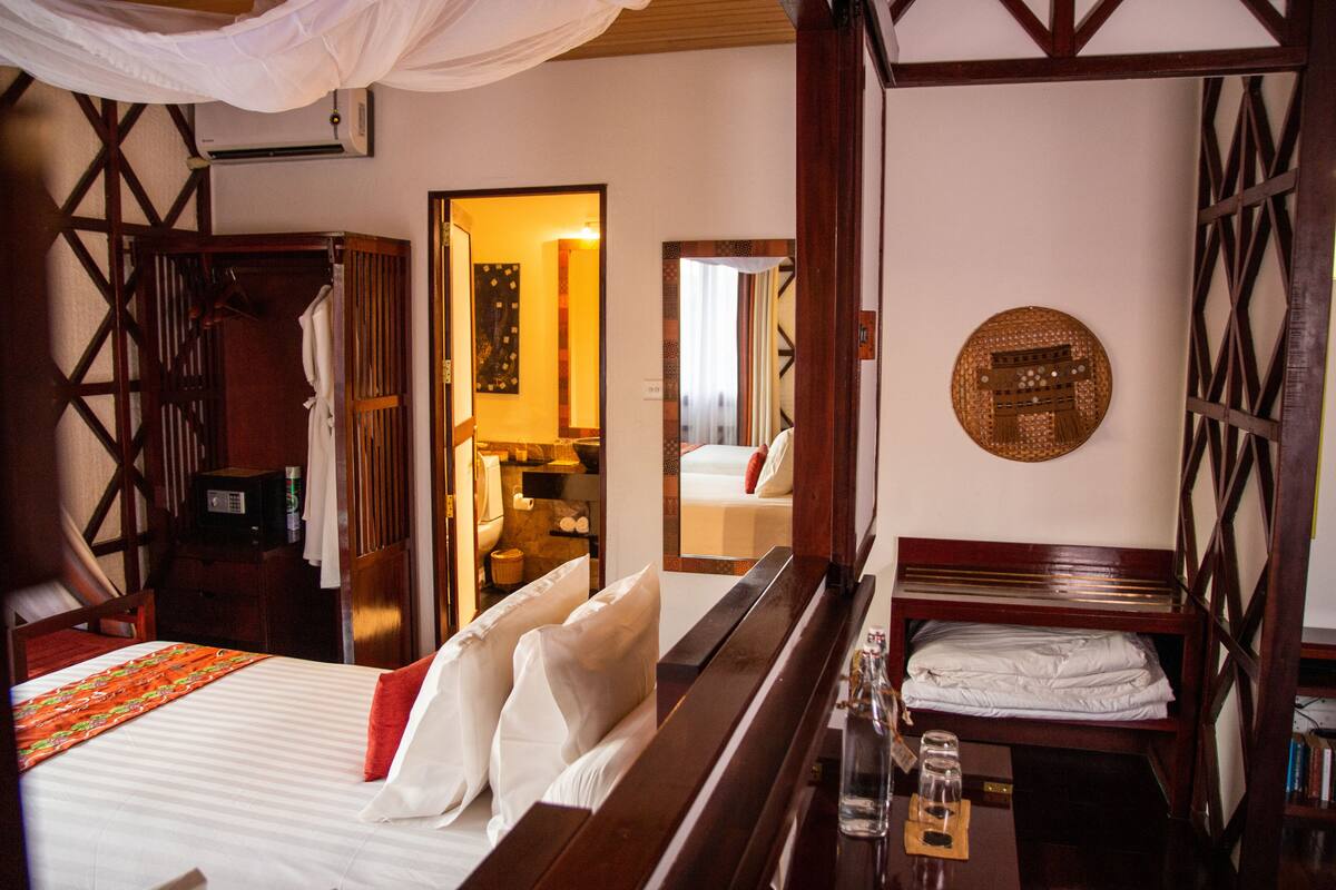 A hotel room with a bed, bedside table, and a mirror.