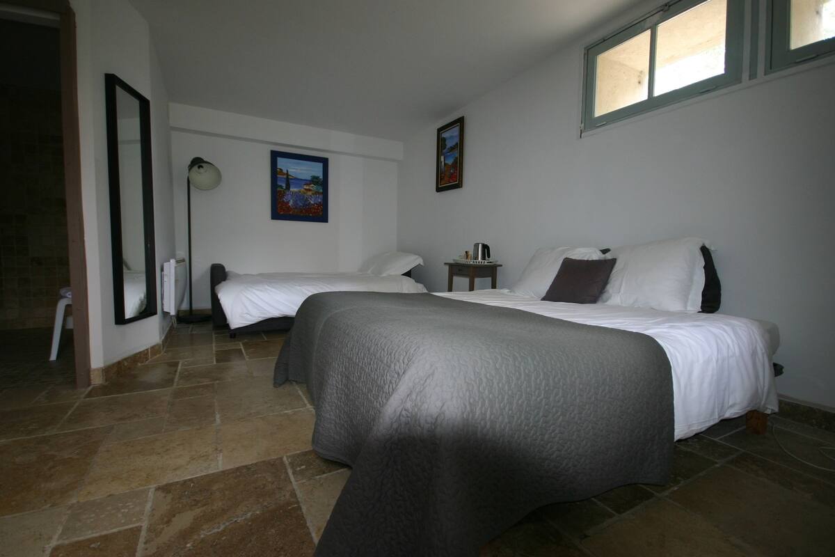 Une chambre d’hôtel avec deux lits, une petite table, une lampe et des œuvres d’art accrochées aux murs.