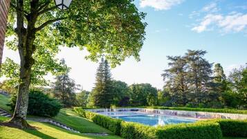 Un área de piscina con vista despejada, rodeada de setos y árboles cuidados.