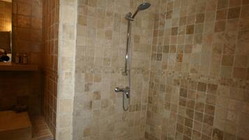 A bathroom with a shower, tiled walls, a sink, and a trash bin.