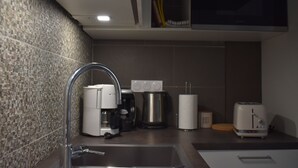 Een moderne keuken met een spoelbak van roestvrij staal, een koffiezetapparaat, een broodrooster en een magnetron.