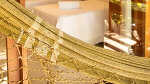 A hammock in a room with two beds and a view of greenery outside.