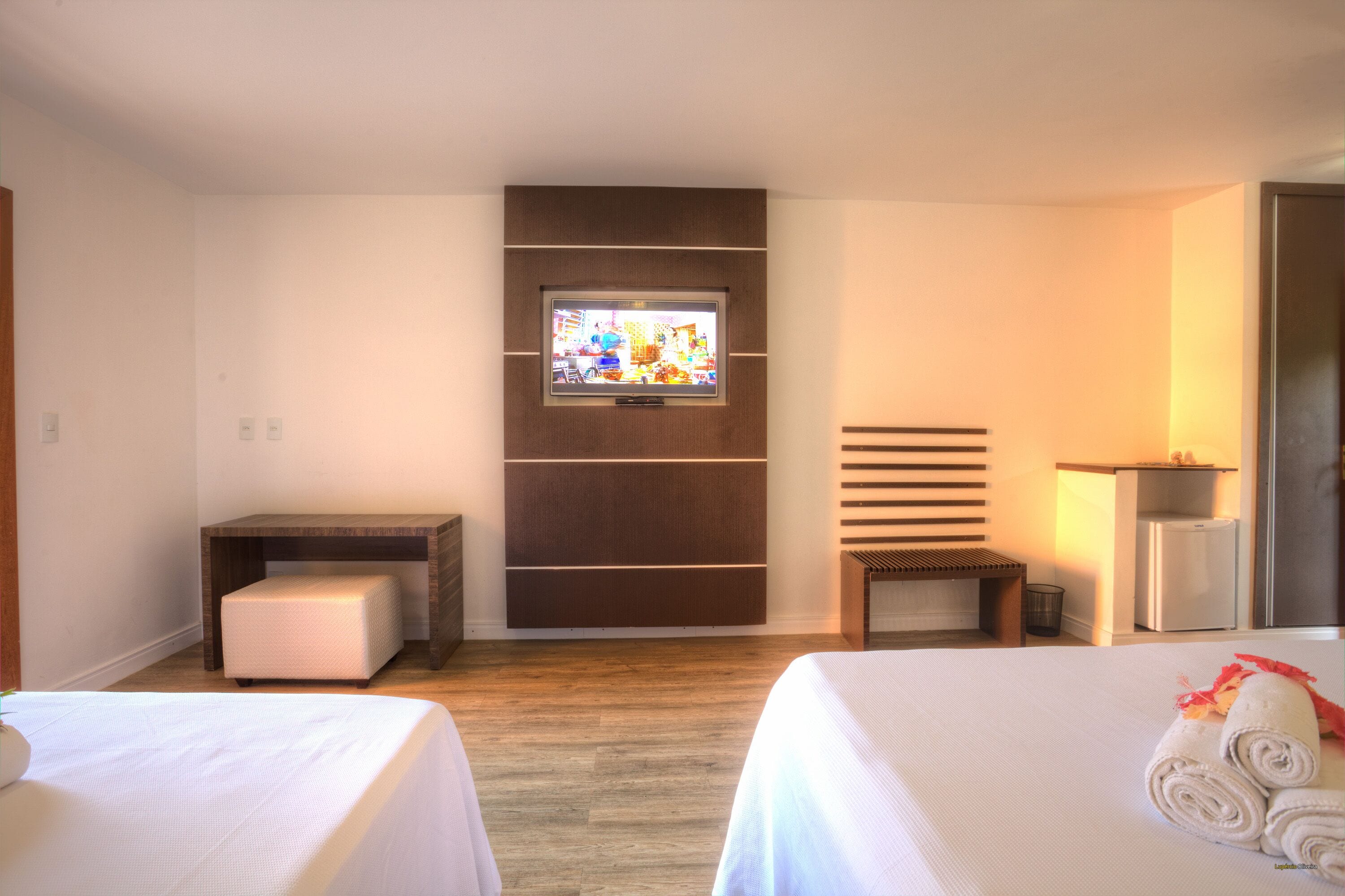 A hotel room with two beds, a television on the wall, a small desk, and a chair.