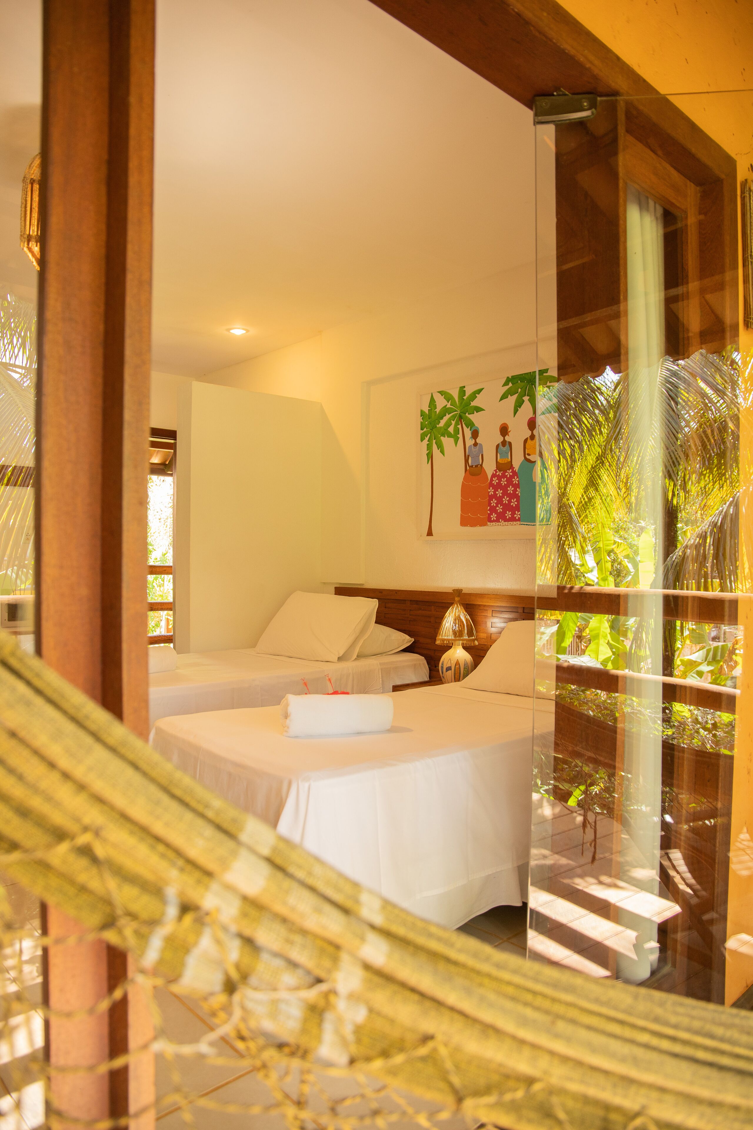 Habitación de hotel con dos camas, un ventanal con vistas a palmeras y un cuadro en la pared.