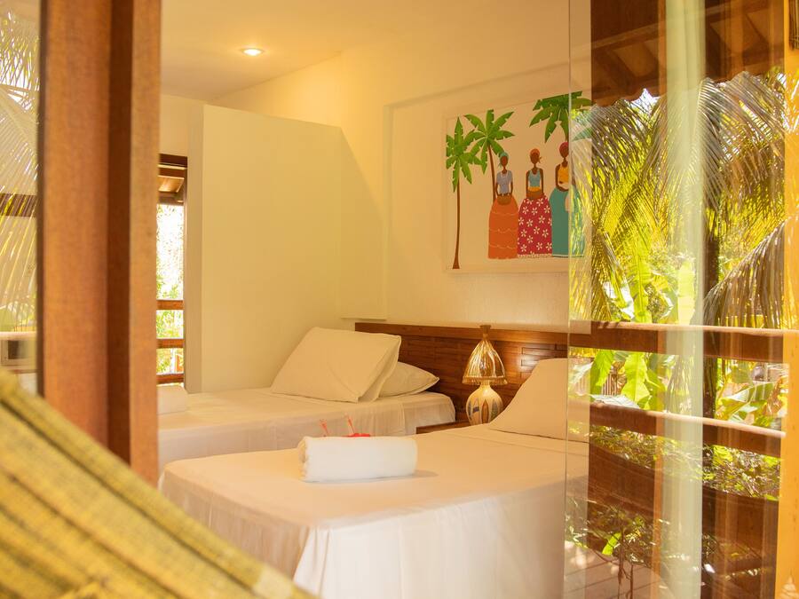 A hotel room with two beds, a large window with a view of palm trees, and a painting on the wall.