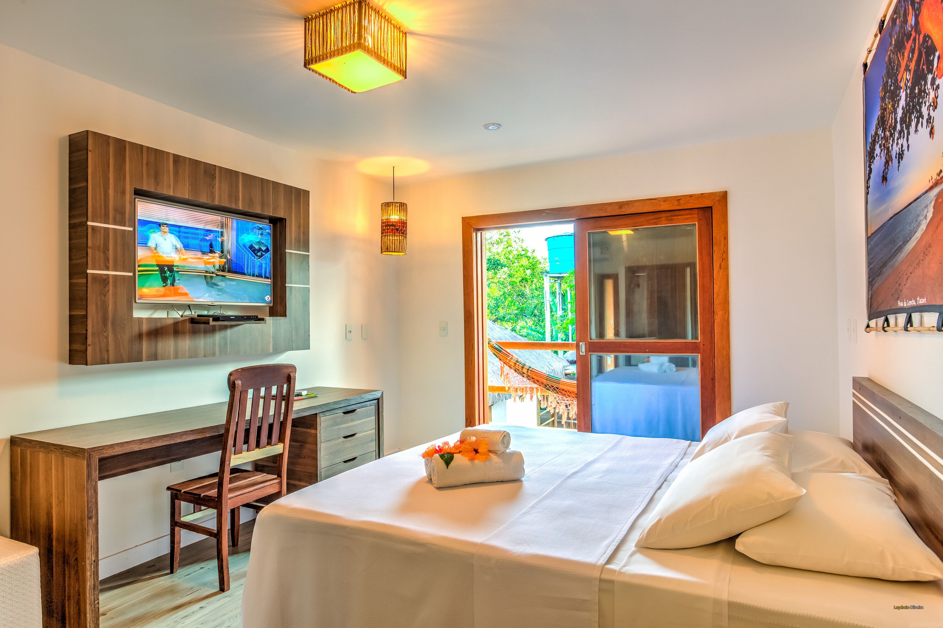 Habitación de hotel con cama, escritorio, silla, televisión y vistas al exterior.