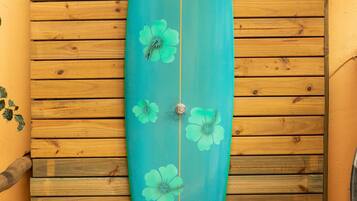 A surfboard leaning against a wooden wall with horizontal planks.