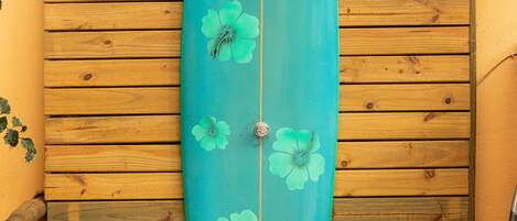 A surfboard leaning against a wooden wall with horizontal planks.