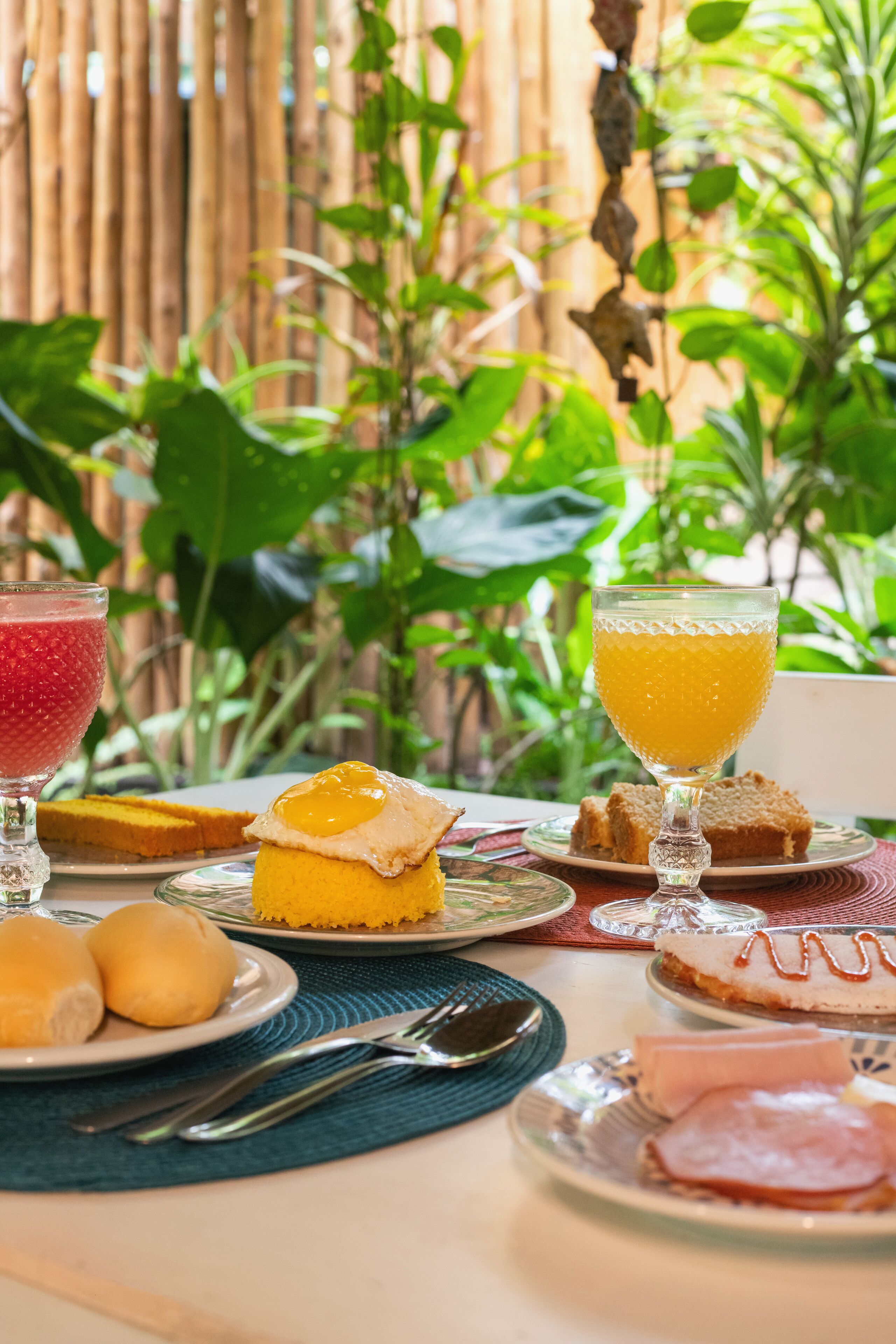 Une table de petit-déjeuner avec divers aliments et boissons, le tout disposé sur un fond de verdure.