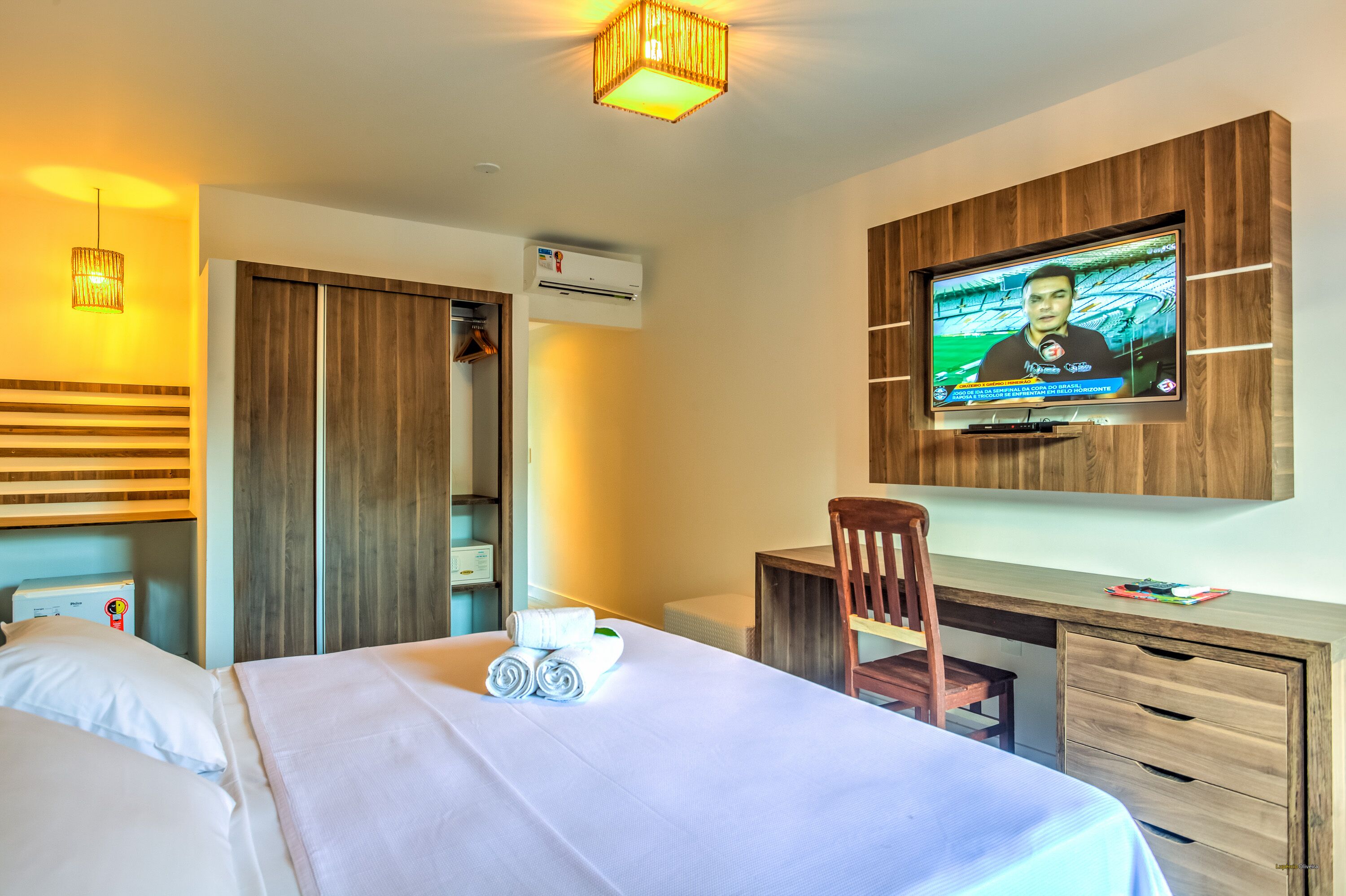 Ein Hotelzimmer mit Bett, Schreibtisch, Fernseher und Kleiderschrank.