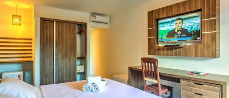 Ein Hotelzimmer mit Bett, Schreibtisch, Fernseher und Kleiderschrank.