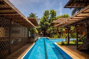 Una piscina con un deck de madera y una zona cubierta en un lateral.