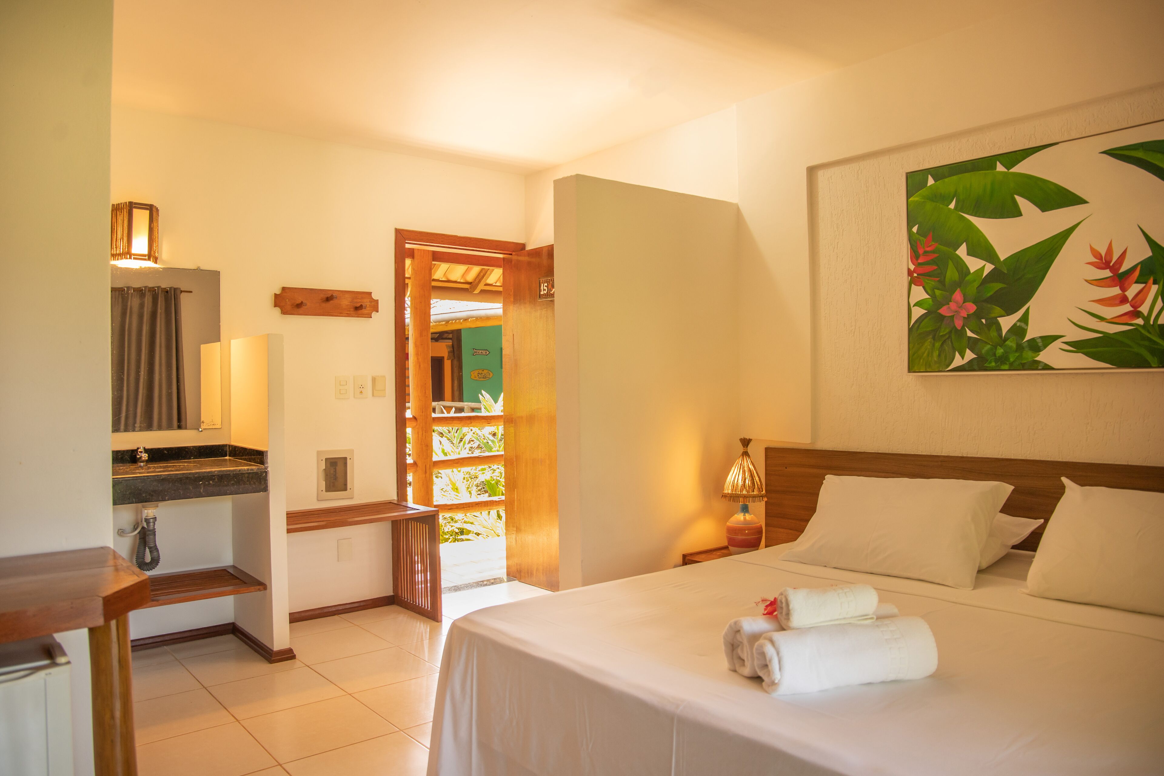 Habitación de hotel con cama, escritorio, baño y puerta que da a un balcón.