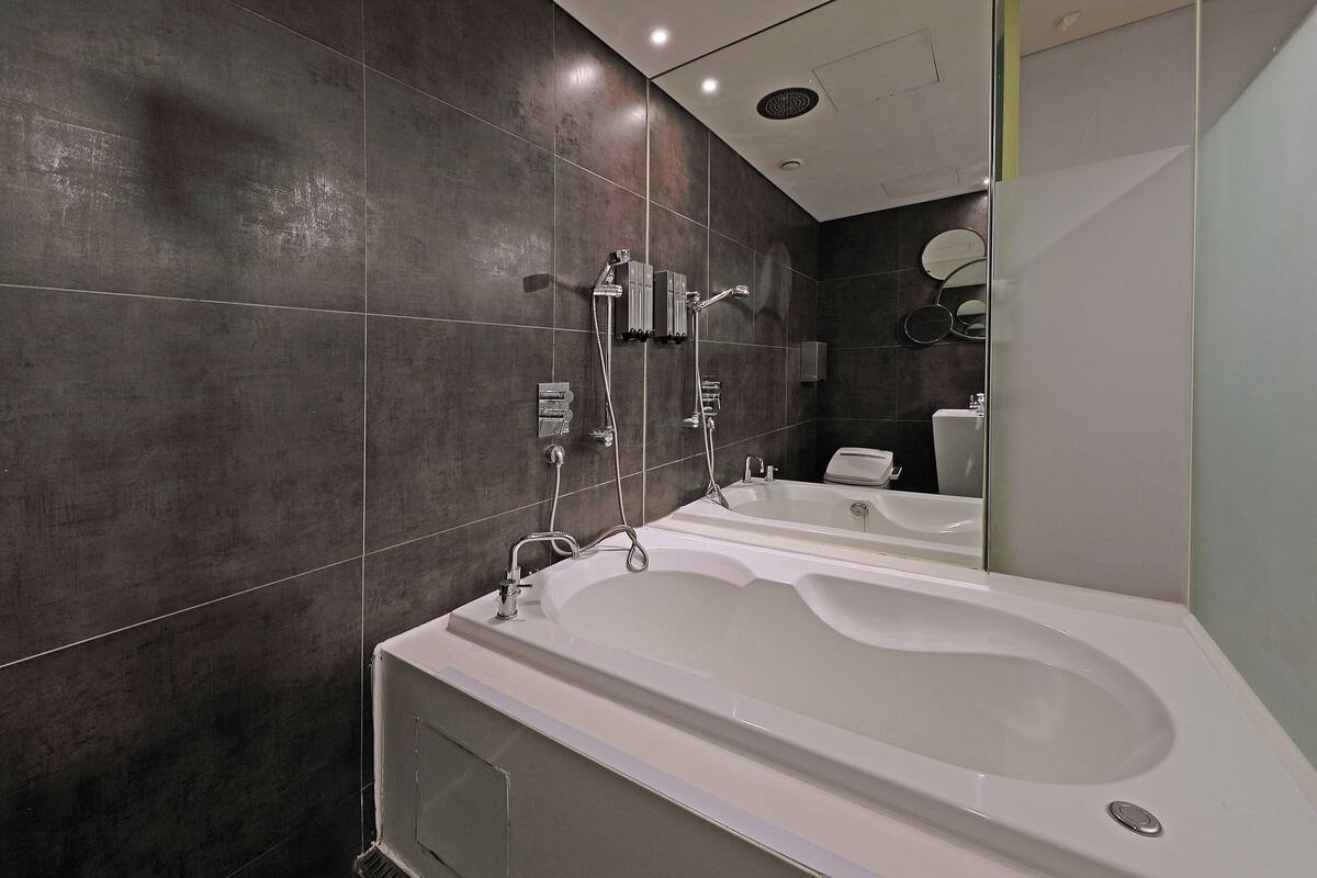 A modern bathroom with a large bathtub, a separate shower area, and a toilet.