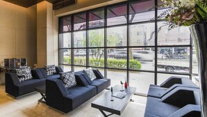 A modern lounge area with dark sofas and a coffee table, large windows offering a view of the street and parked cars. - Sota Stay Gundae (Seoul)