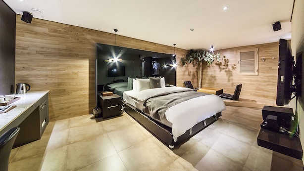 Un dormitorio moderno con una cama grande, mesitas de noche, un escritorio y un televisor.